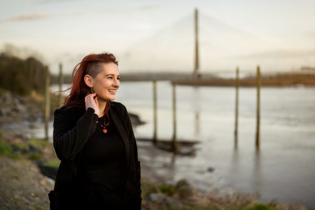 Cathy smiling looking out on the river Suir with the Bridge in the background